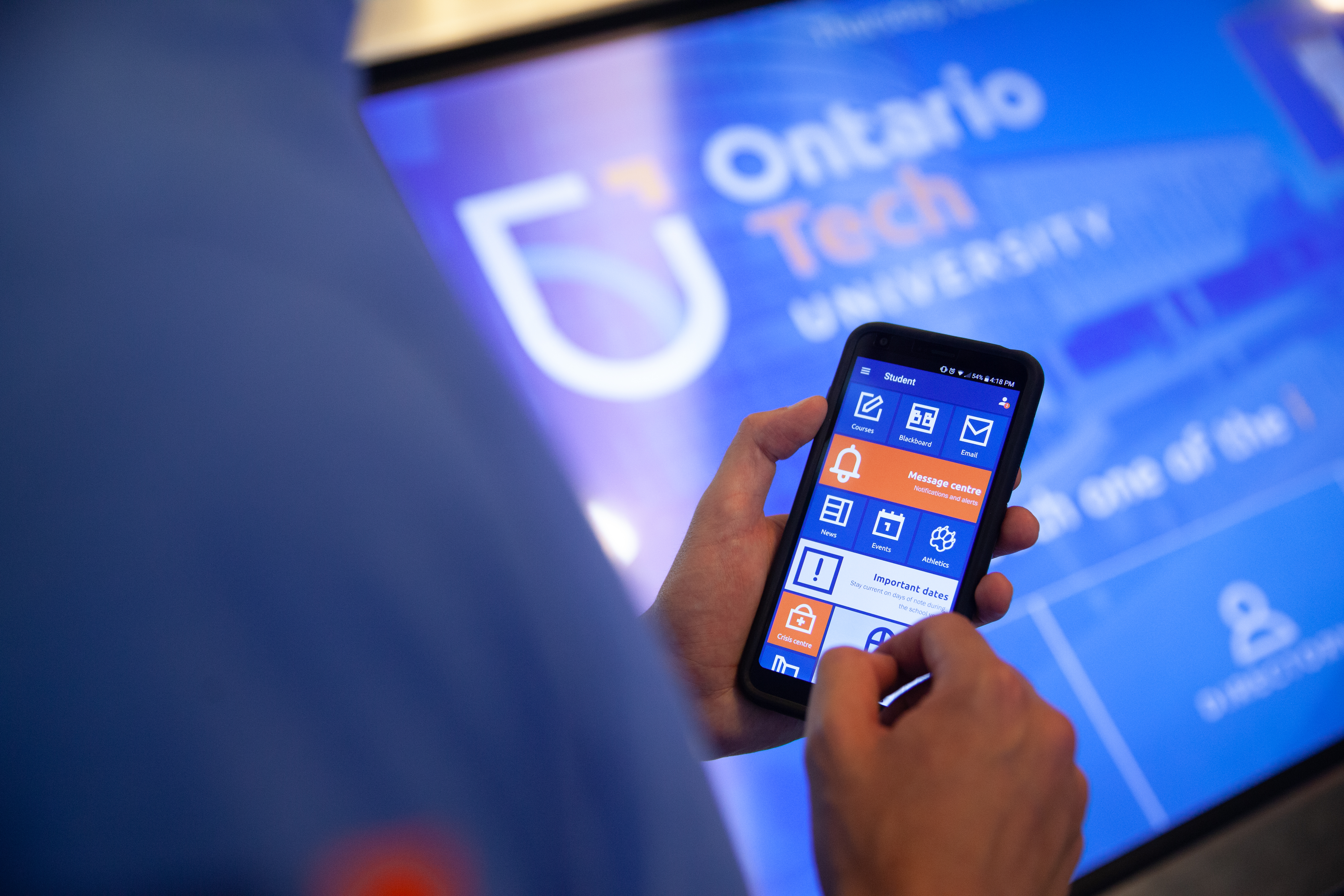 a picture of a person holding a phone with an Ontario Tech app open. 