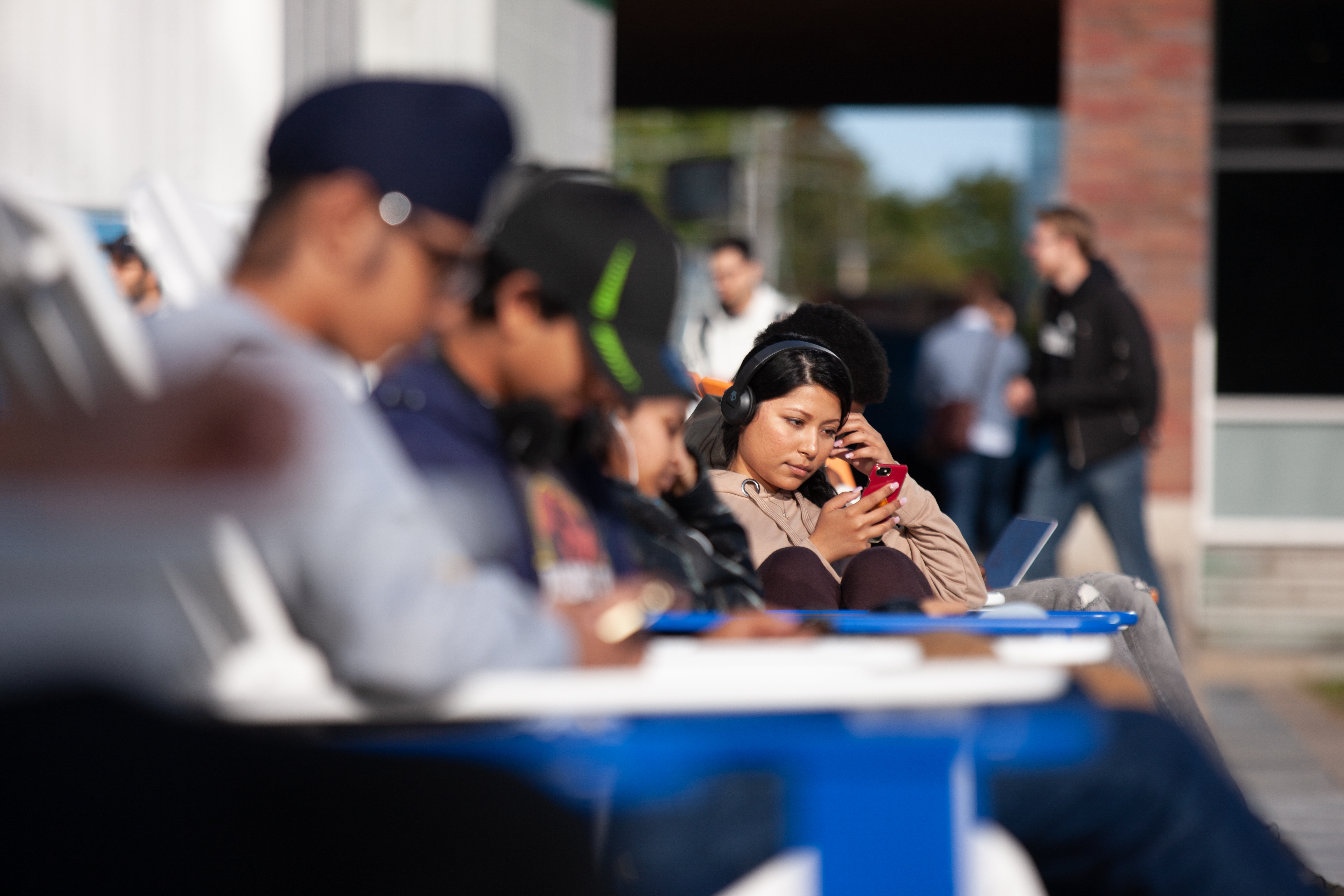 an individual sitting down looking at their phone, the photo has students surround blurred.
